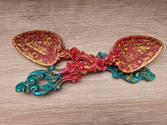 Decorative spoon with gold, red, and blue colors on a wooden surface