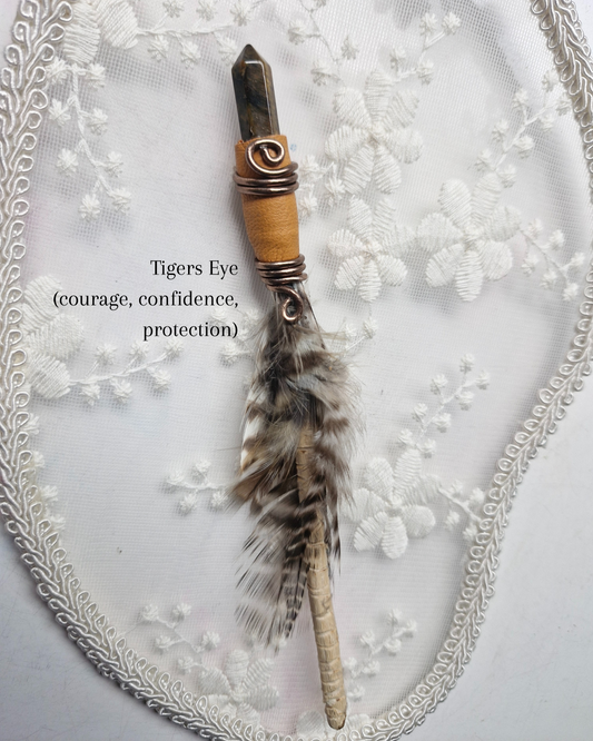 Crystal Tiger's Eye wand with feather on a decorative background