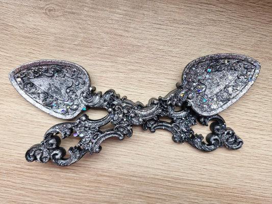 Decorative silver spoon with intricate designs on a wooden surface