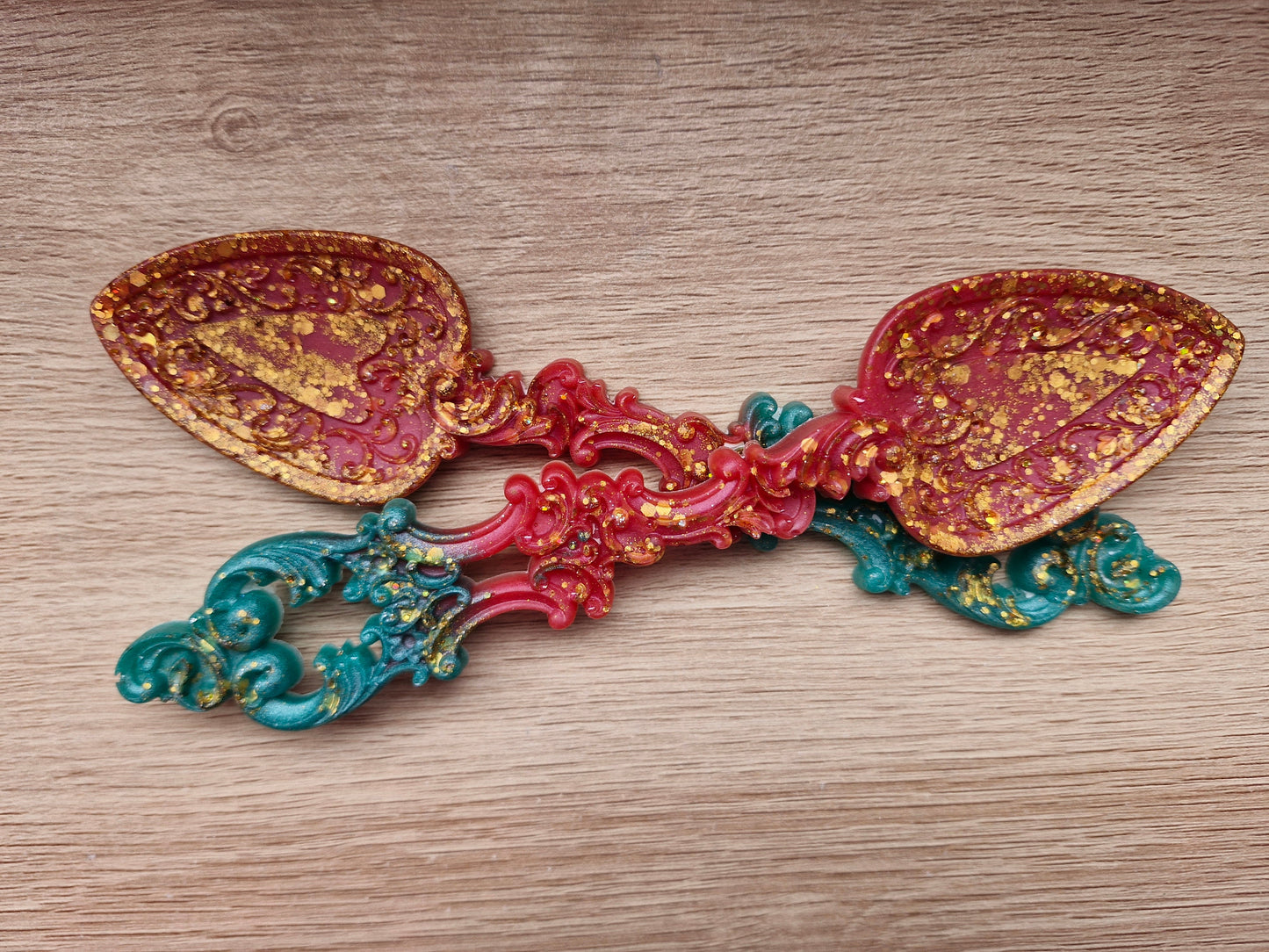 Decorative spoon with gold, red, and blue colors on a wooden surface