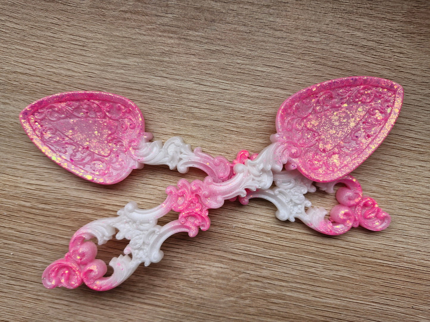 Pink and white resin spoon on a wooden surface