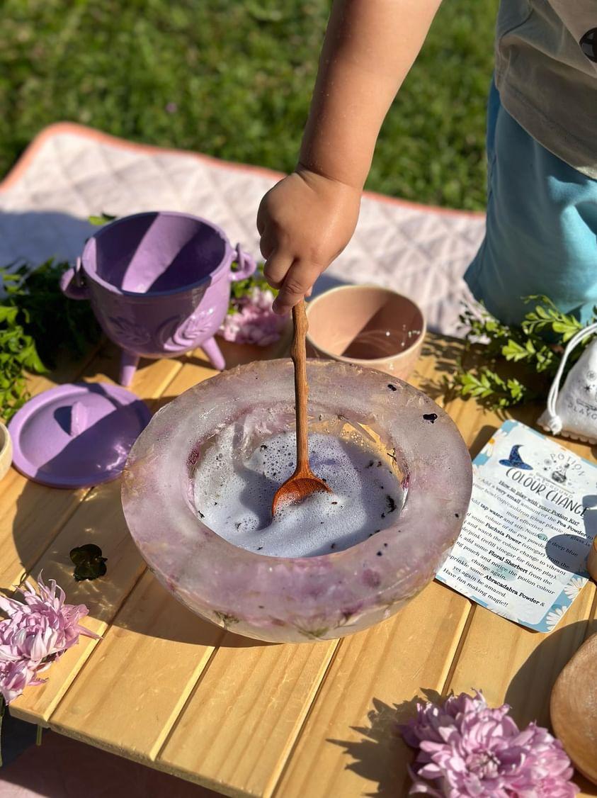 Child mixing potions in a frozen flower bowl