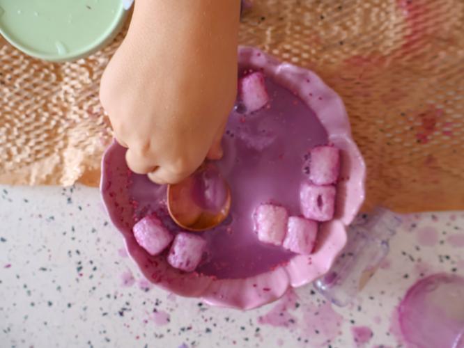 childs hand playing with potion kit in a bowl
