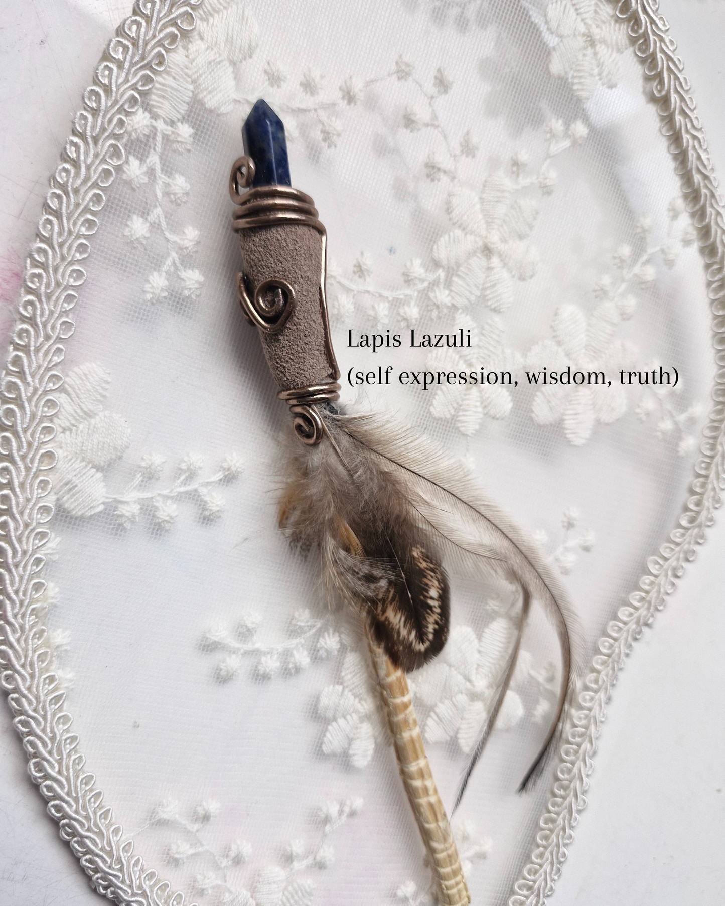 Lapis Lazuli crystal wand with feather on a decorative background