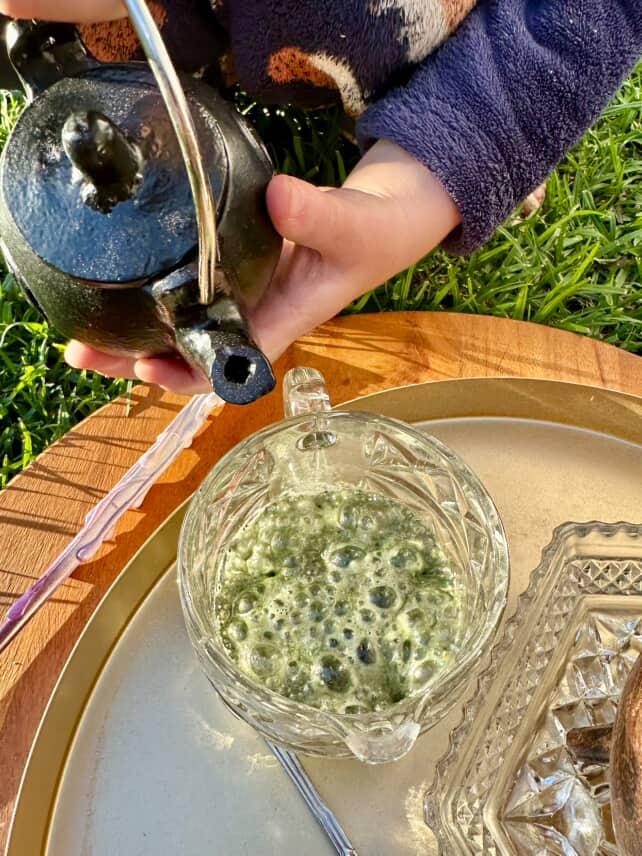 gree potion bubbles in glass bowl with black cast iron cauldron